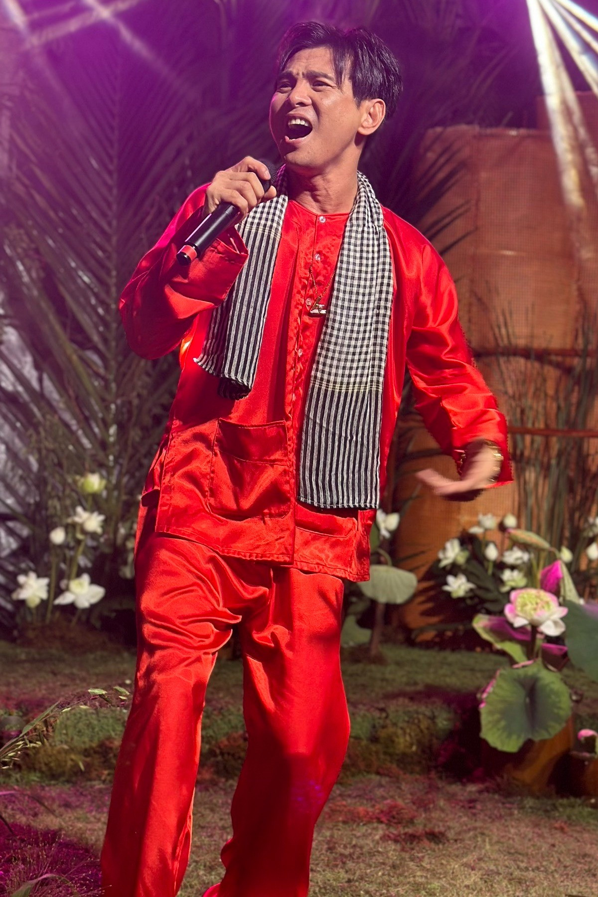 Ca sĩ Lâm Hùng mặc đồ bà ba đỏ, mang khăn rằn phục vụ văn nghệ trong tiệc cưới Puka - Gin Tuấn Kiệt.