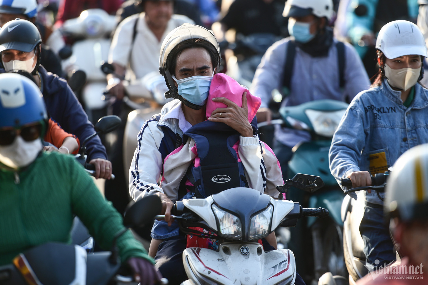 Lộ trình bị thay đổi, một người đi xe máy một tay ôm trẻ nhỏ một tay vặn ga và bóp phanh để di chuyển.