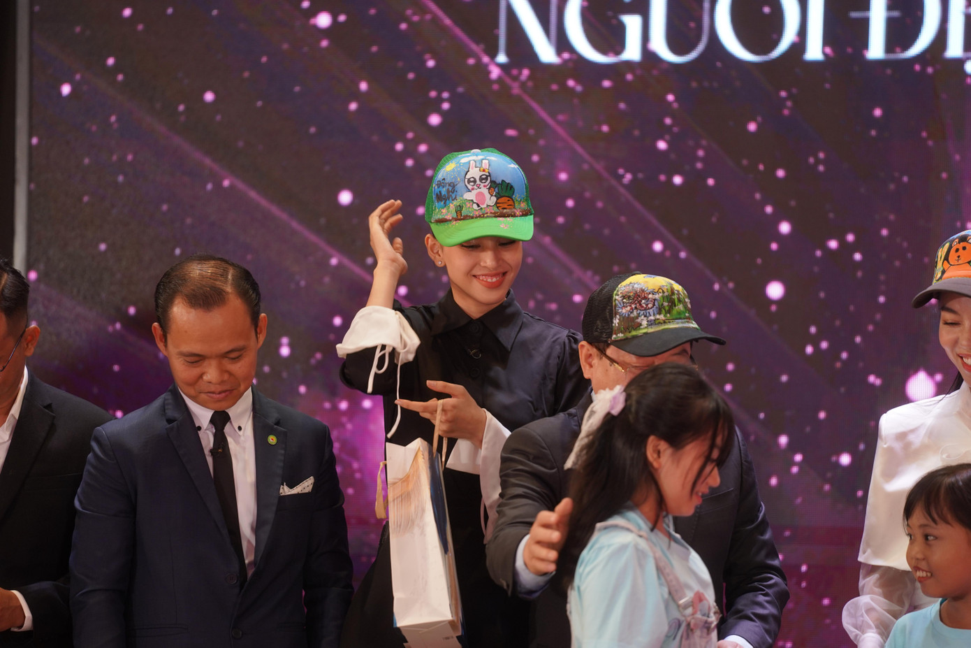 Sau phần thuyết trình nhân ái của Mỹ Anh và Lê Thanh Trúc, đại diện lớp Nét chữ Xinh và các bệnh nhi ung thư tại Bệnh viện Nhi đồng 2 gửi những món quà mang nhiều giá trị tinh thần cho ban giám khảo. Nhà báo Lê Xuân Sơn, bà Phạm Kim Dung và Tiểu Vy niềm nở đón nhận quà tặng. Hình ảnh Hoa hậu Việt Nam 2018. Hình ảnh Tiểu Vy háo hức khi đội trên đầu món quà của các bệnh nhi để lại ấn tượng đẹp.