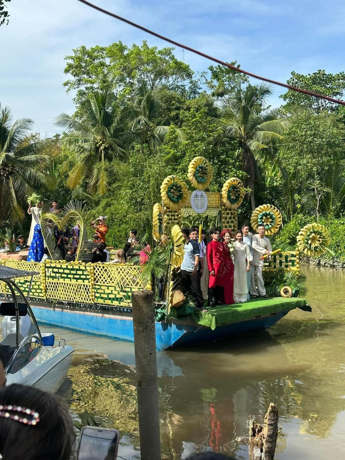 Gin Tuấn Kiệt &quot;đưa nàng về dinh&quot; trên phà rước dâu trang trí thủ công bằng lá dừa, cổng chào đính kết hoa hoành tráng. Theo chia sẻ của Puka, cô được cả họ trông lấy chồng nên buộc tổ chức cưới ở Đồng Tháp. Gin Tuấn Kiệt lại là con một nên phải tổ chức riêng ở TPHCM để họ hàng đến chúc mừng.