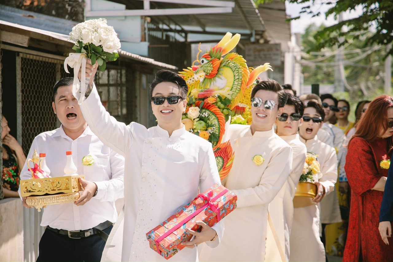 Chú rể và đội bê tráp gây chú ý khi mang kính râm tiến vào nhà cô dâu. TiTi cho biết nhà trai là những người bạn thân, chịu khó di chuyển xa từ TPHCM xuống Cần Thơ để hỗ trợ nam ca sĩ trong ngày vui.
