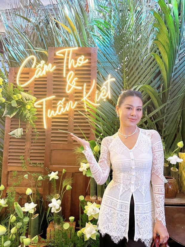 Nam Thư cũng diện đồ bà ba cách tân dự tiệc cưới đồng nghiệp. Trước đó cô check-in trước cổng hoa được trang trí bằng lá dừa, cau và hoa tươi.