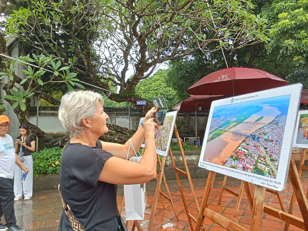 Du khách quốc tế quan tâm tới những hình ảnh tiêu biểu của Hà Nội. Bà Jeanette Freudiger đến từ Thụy Sĩ (trái) ấn tượng với bức ảnh sông Hồng nhìn từ trên cao của tác giả Phạm Hùng. "Bây giờ tôi hiểu vì sao dòng sông nổi tiếng chảy trong lòng thành phố của các bạn có tên gọi như vậy, màu đỏ phù sa của dòng sông rất đặc trưng. Nó nổi bật trên nền xanh ngắt của rất nhiều cây cối. Dọc theo bờ sông là Hà Nội, với những ngôi nhà nhỏ mọc lên san sát, rất đặc trưng và thú vị”, bà nói.