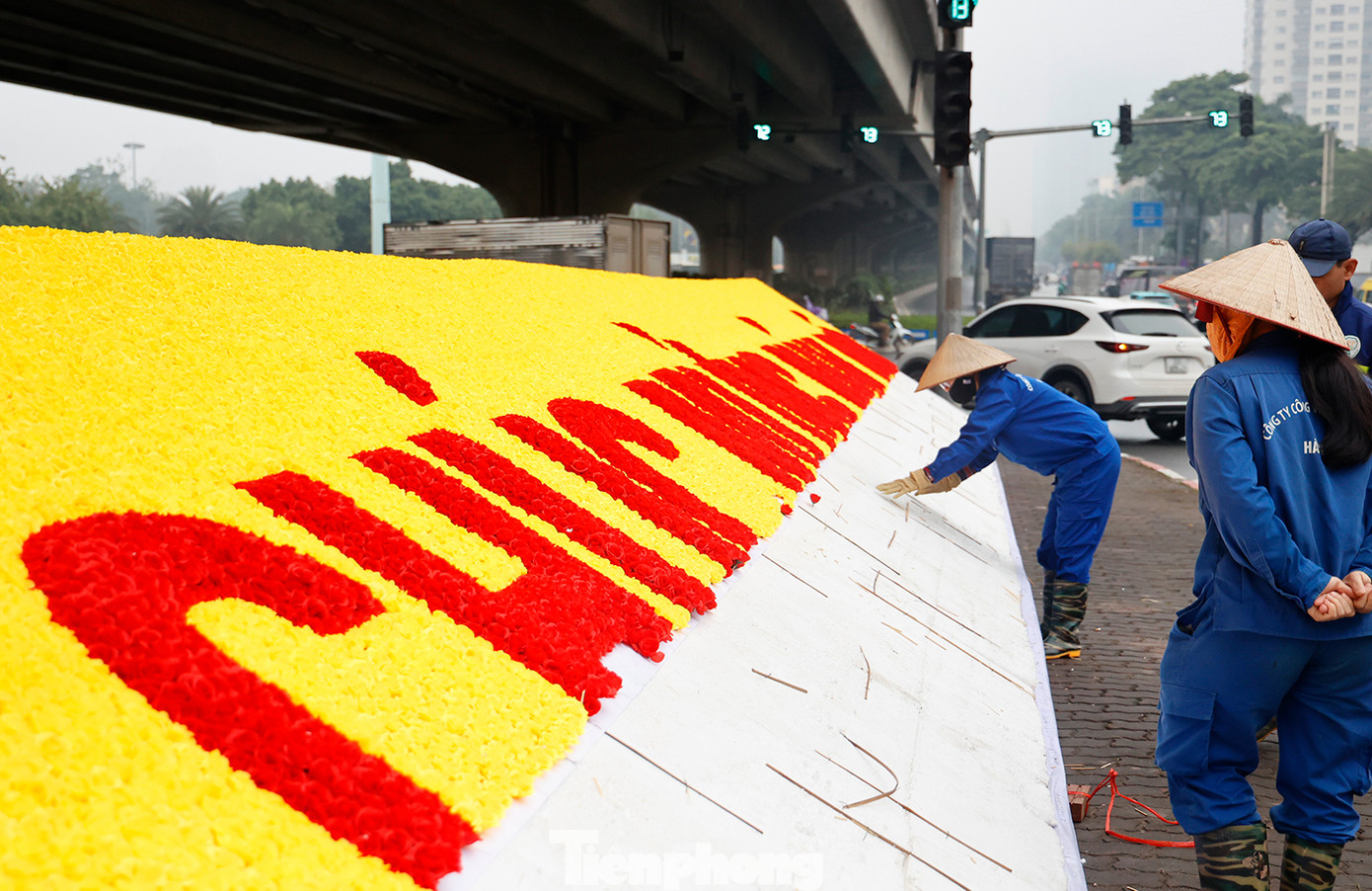 Công nhân công ty cây xanh Hà Nội trang trí dòng chữ: "Chúc mừng năm mới" tại ngã tư Đại lộ Thăng Long.