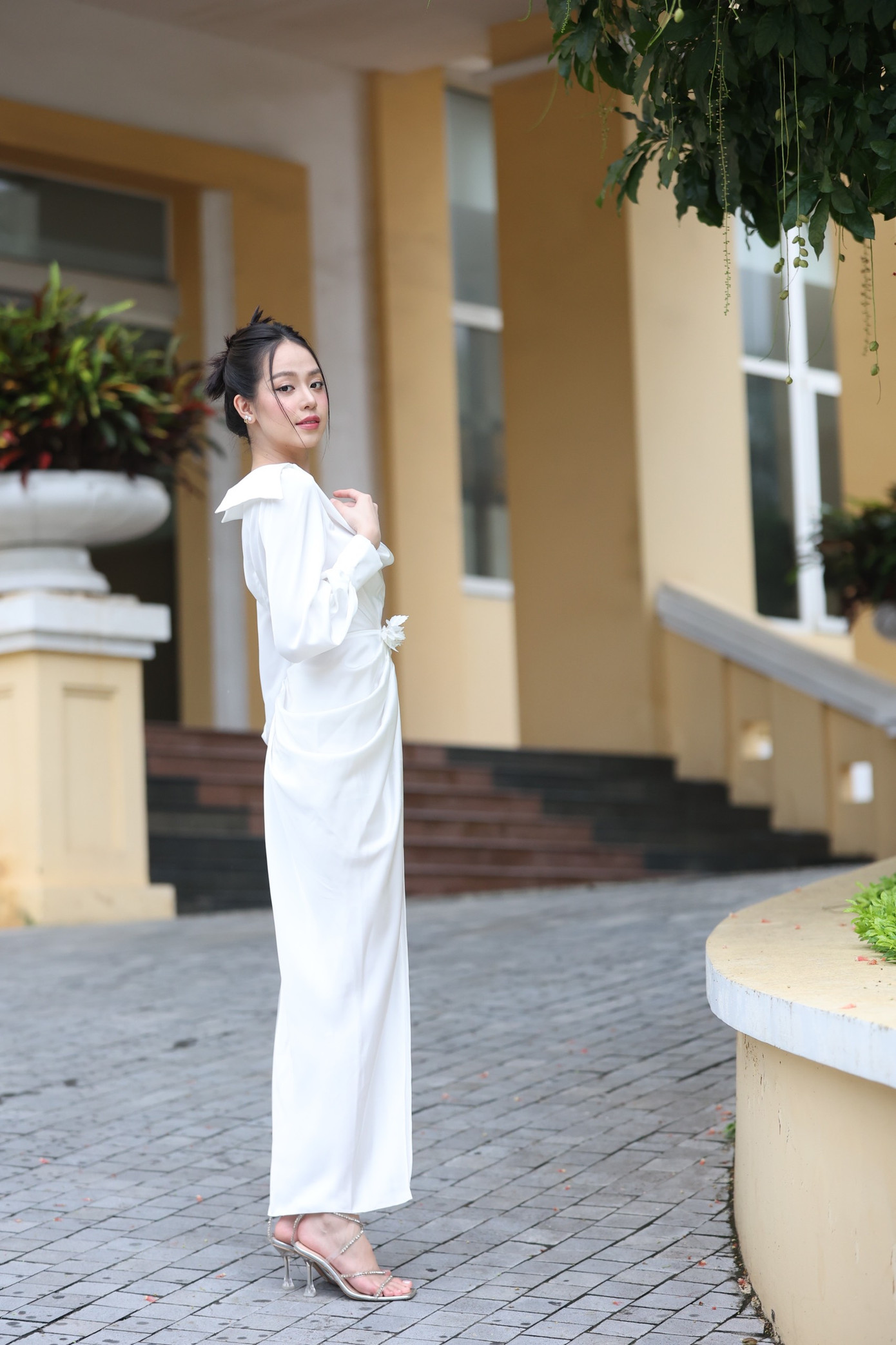 Hoa hậu Thanh Thuỷ diện váy trắng trễ vai kiểu cổ tim duyên dáng. Người đẹp búi tóc sang trọng và trang điểm nhẹ nhàng.