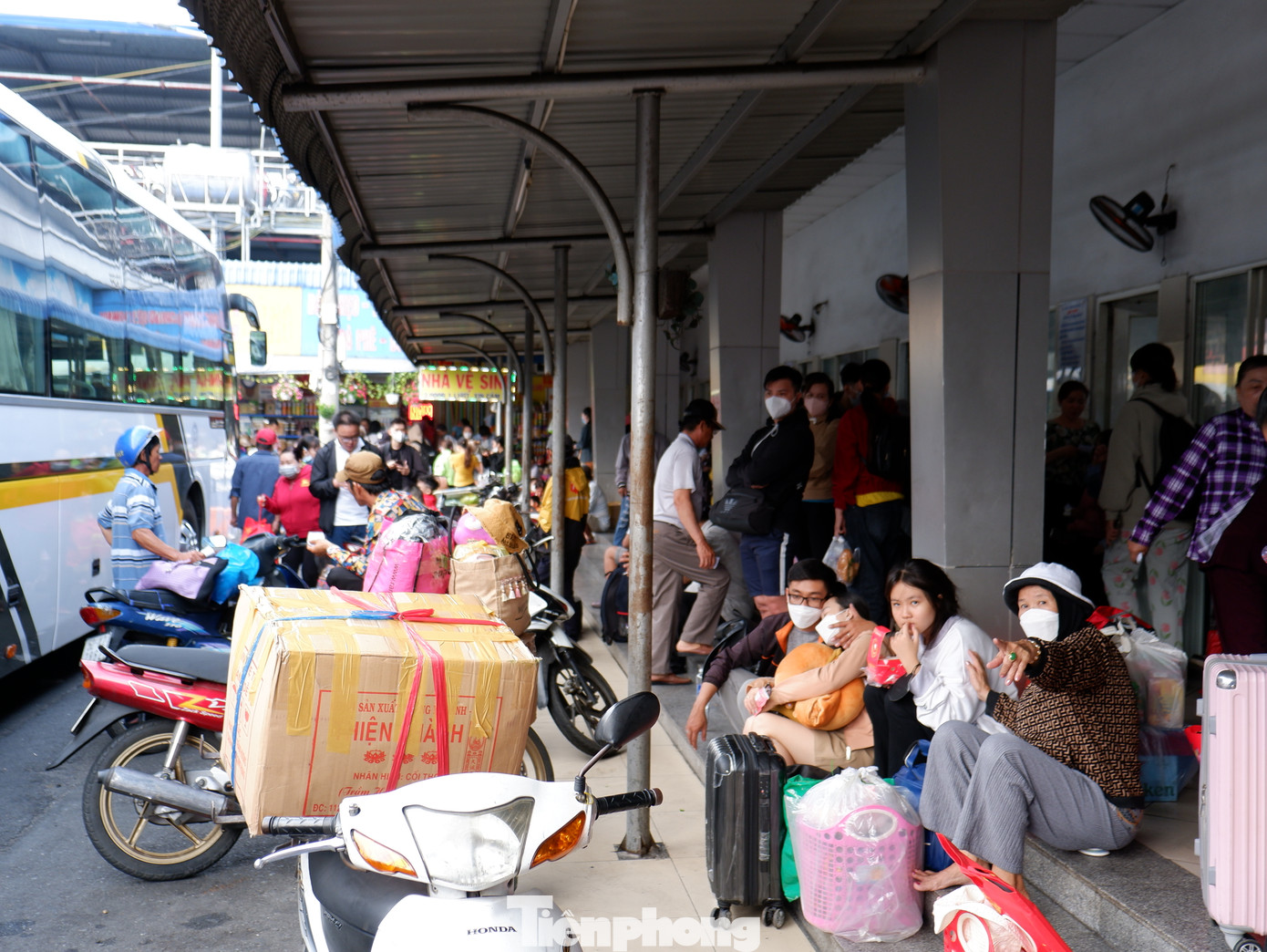 Lượng hành khách tăng cao, nhiều người ngồi tạm trước các bậc thềm chờ đến giờ lên xe.