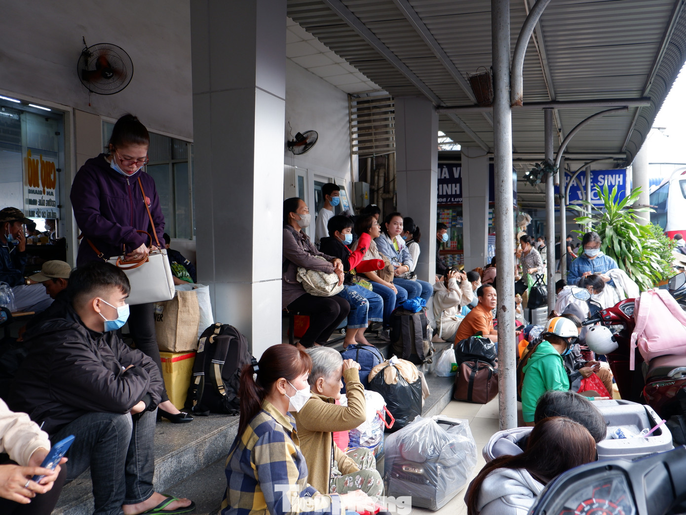 Lượng hành khách tăng cao, nhiều người ngồi tạm trước các bậc thềm chờ đến giờ lên xe.