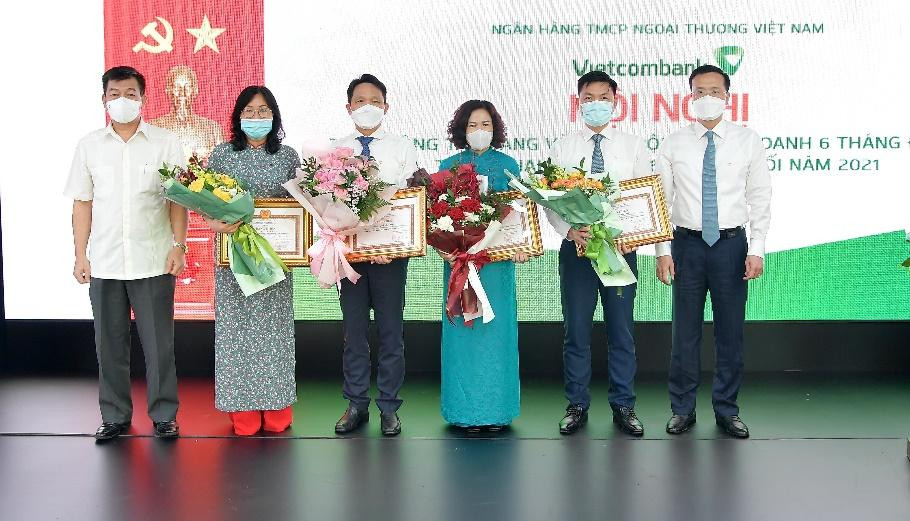 Đ/c Nguyễn Đức Phong – Phó Bí thư Đảng ủy Khối DNTW (ngoài cùng bên trái) và đ/c Phạm Quang Dũng – Phó Bí thư phụ trách Đảng bộ, Tổng Giám đốc Vietcombank (ngoài cùng bên phải) trao Bằng khen của Đảng ủy Khối và tặng hoa chúc mừng cho các tổ chức đảng đạt danh hiệu “Trong sạch, vững mạnh” tiêu biểu 5 năm liền (2016-2020) và đảng viên đạt danh hiệu “Hoàn thành xuất sắc nhiệm vụ” 5 năm liền (2016 – 2020)