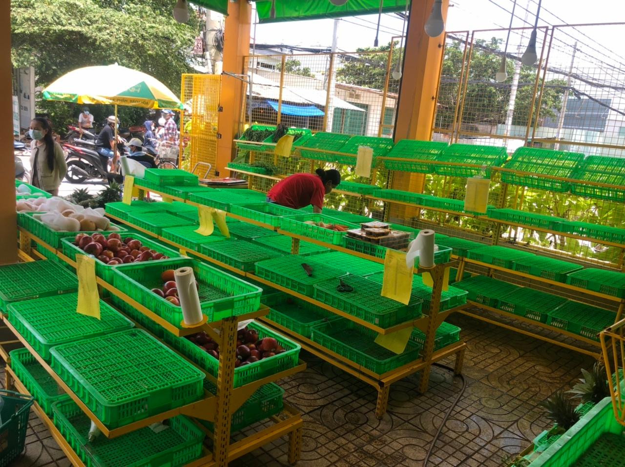 Cả quầy rau trái chỉ còn lại ít táo, lê. Nhân viên dọn dẹp và cho biết hết hàng rau cho buổi chiều