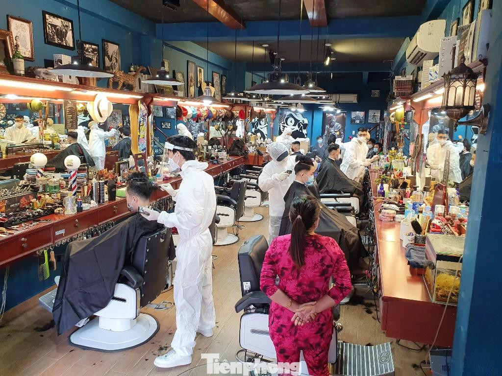 Một tiệm cắt tóc, nhân viên trang bị đồ bảo hộ cẩn thận khi phục vụ khách