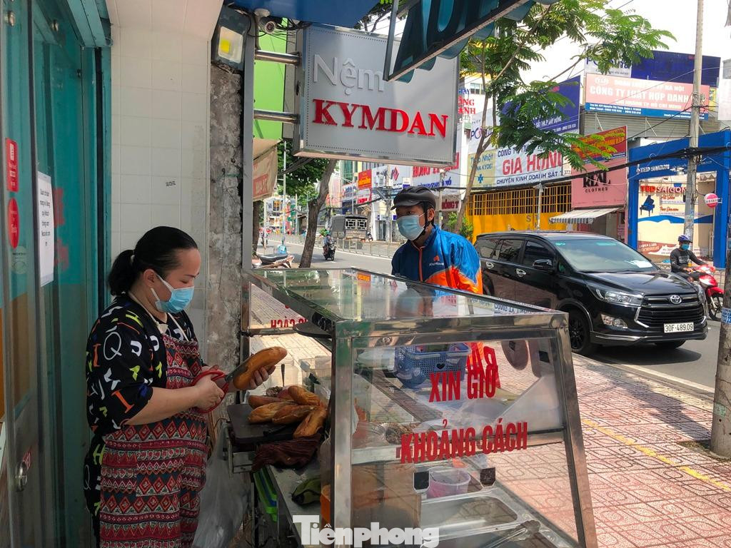 Ngày 17/9, quầy bánh mì trên đường Nguyễn Thị Thập (phường Tân Phong, quận 7) tấp nập khách và shipper chờ mua hàng. “Hôm nay là lần đầu tiên tôi ra đường, gặp ngay quán bánh mì và trà sữa nên mừng quá, tôi mua luôn 10 phần đem về nhà cho mọi người cùng thưởng thức” – anh Thành (ngụ quận 7) chia sẻ. Chỉ trong vòng nửa giờ đồng hồ, shipper liên tục đến lấy hàng. Người bán vừa chế biến, vừa gọi điện thoại “hối” người giao vì “cháy hàng” bánh mì. Mới hơn 9 giờ sáng, tủ bánh mì đã hết nhưng vẫn còn nhiều khách đến mua… Ngày 17/9, quầy bánh mì trên đường Nguyễn Thị Thập (phường Tân Phong, quận 7) tấp nập khách và shipper chờ mua hàng. “Hôm nay là lần đầu tiên tôi ra đường, gặp ngay quán bánh mì và trà sữa nên mừng quá, tôi mua luôn 10 phần đem về nhà cho mọi người cùng thưởng thức” – anh Thành (ngụ quận 7) chia sẻ. Chỉ trong vòng nửa giờ đồng hồ, shipper liên tục đến lấy hàng. Người bán vừa chế biến, vừa gọi điện thoại “hối” người giao vì “cháy hàng” bánh mì. Mới hơn 9 giờ sáng, tủ bánh mì đã hết nhưng vẫn còn nhiều khách đến mua…