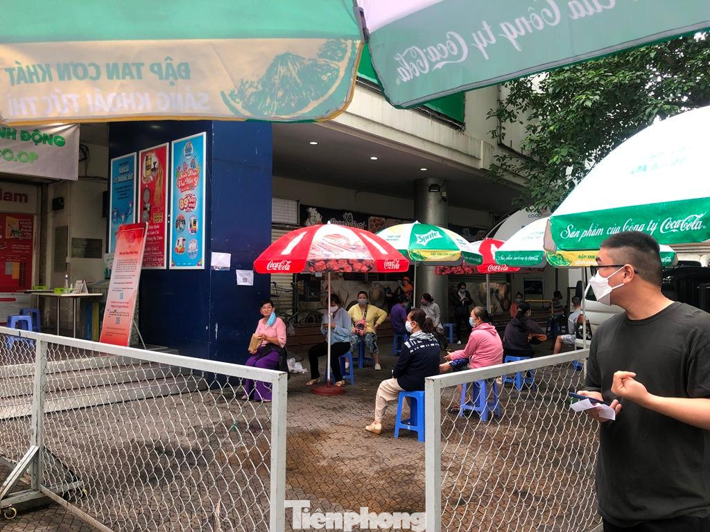 Những người gần đến lượt vào siêu thị đang được chờ gọi tên. "Tôi đi chợ cho gia đình và cả nhà hàng xóm, lần khác họ đi sẽ mua hộ lại cho mình để đỡ mất thời gian." - chị Lan (ngụ Q.10) nói.