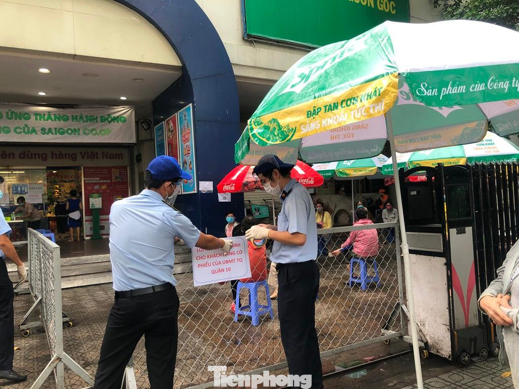 Lực lượng bảo vệ vừa điều phối người dân xếp hàng, giữ an ninh trật tự và hỗ trợ đo nhiệt độ, khai báo y tế trước khi khách vào siêu thị.