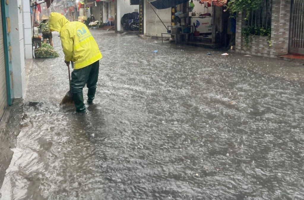 Ngập trên phố Bùi Xương Trạch, quận Thanh Xuân, nhân viên Cty Thoát nước đã khai thông các hố ga thu nước để giảm ngập nặng hơn.