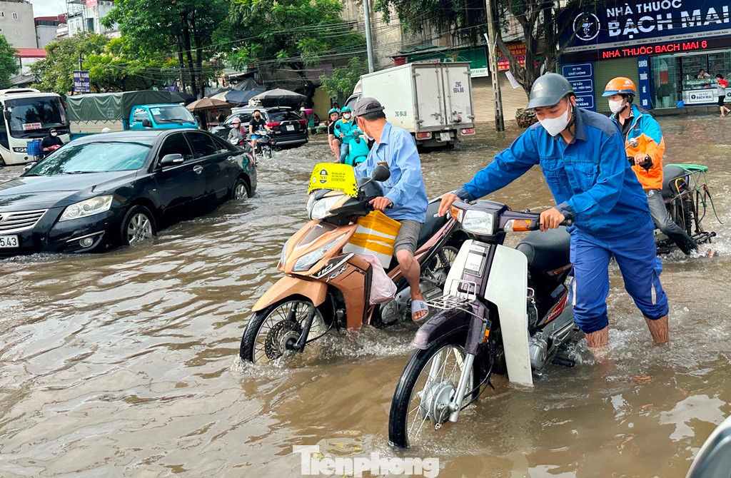 Cố gắng đi qua khu vực ngập, nhiều phương tiện bị chết máy. Người tham gia giao thông phải lội nước, dắt xe.