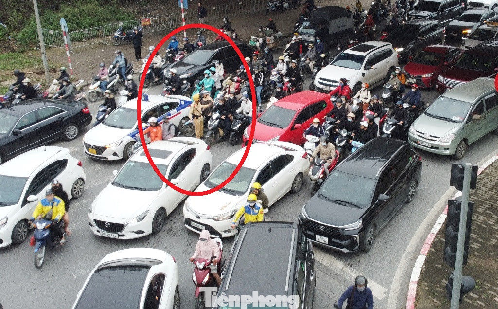 Khi ùn tắc từ tất cả các hướng đến nút giao đại lộ Thăng Long với Lê Quang Đạo, CSGT làm việc tại đây bị các dòng phương tiện ùn tắc vây kín (vòng tròn đỏ).