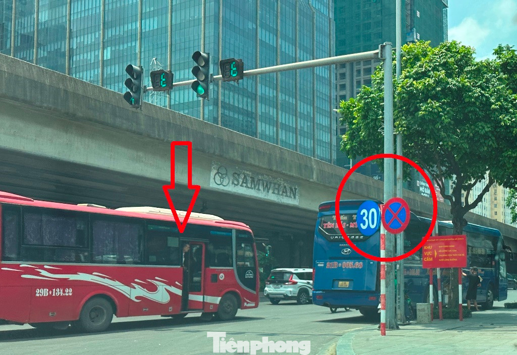 Xe khách kéo dài diễu phố trên đường Phạm Hùng, phụ xe mở cửa thò đầu ra ngoài vẫy khách, bên cạnh là biển cấm dừng đỗ và cấm đi chậm dưới 30 km/h