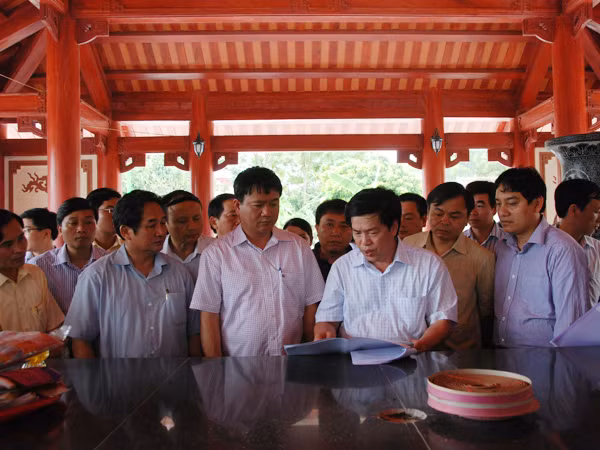 Bộ trưởng Đinh La Thăng và Bí thư thứ nhất Nguyễn Đắc Vinh nghe báo cáo về dự án Khu di tích lịch sử Truông Bồn bên ngôi mộ tập thể TNXP Truông Bồn.