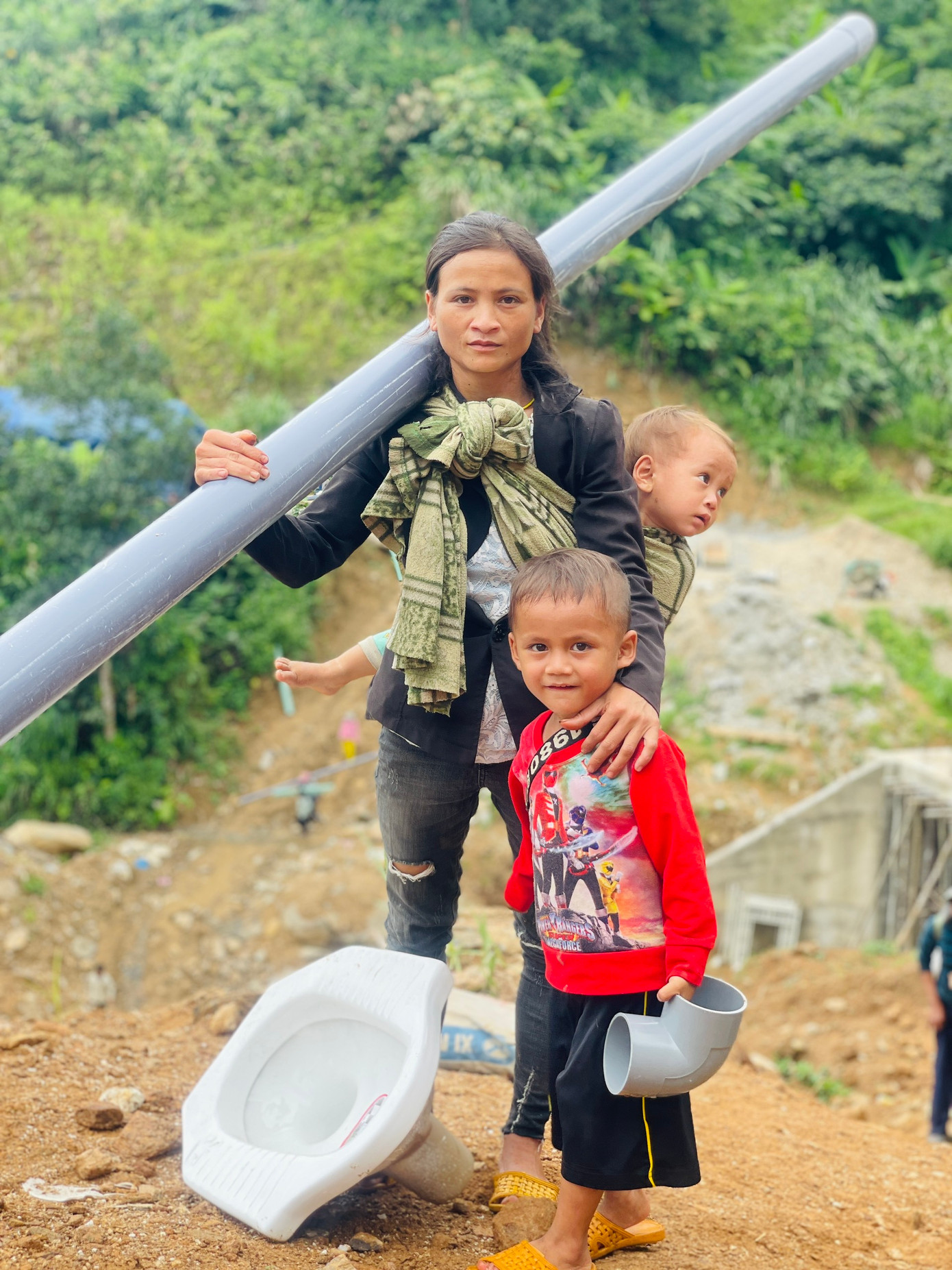 Mẹ con cùng vận chuyển vật liệu về làng