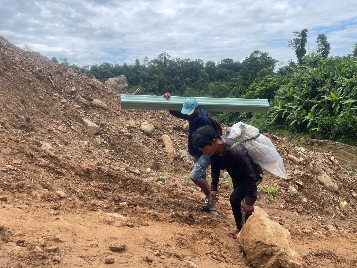 Mọi người cùng nhau lội bộ vận chuyển vật liệu về làng.