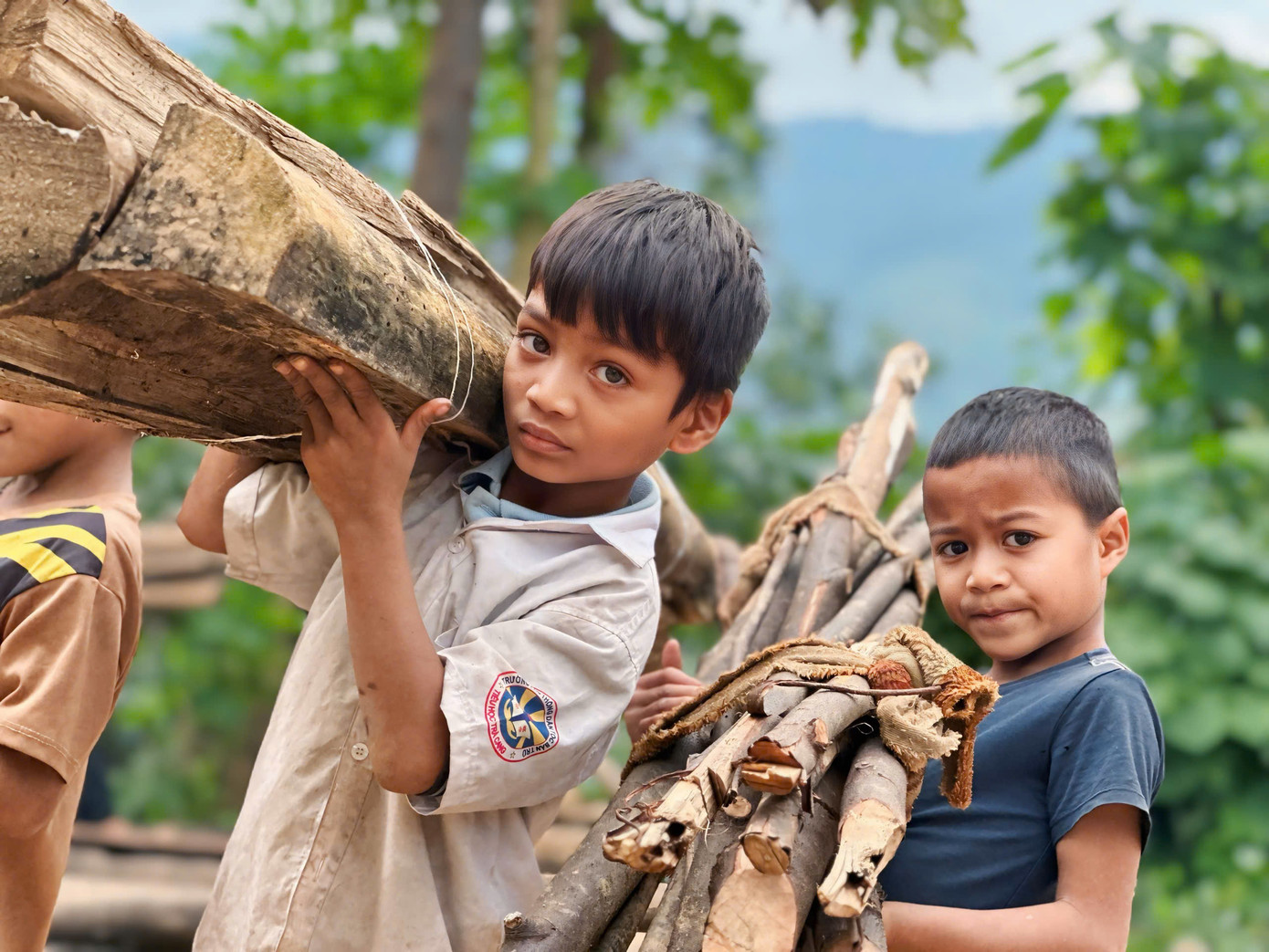 Đáng yêu hình ảnh các bạn nhỏ xung phong vác củi giúp anh chị chuẩn bị bữa ăn nhân ái.