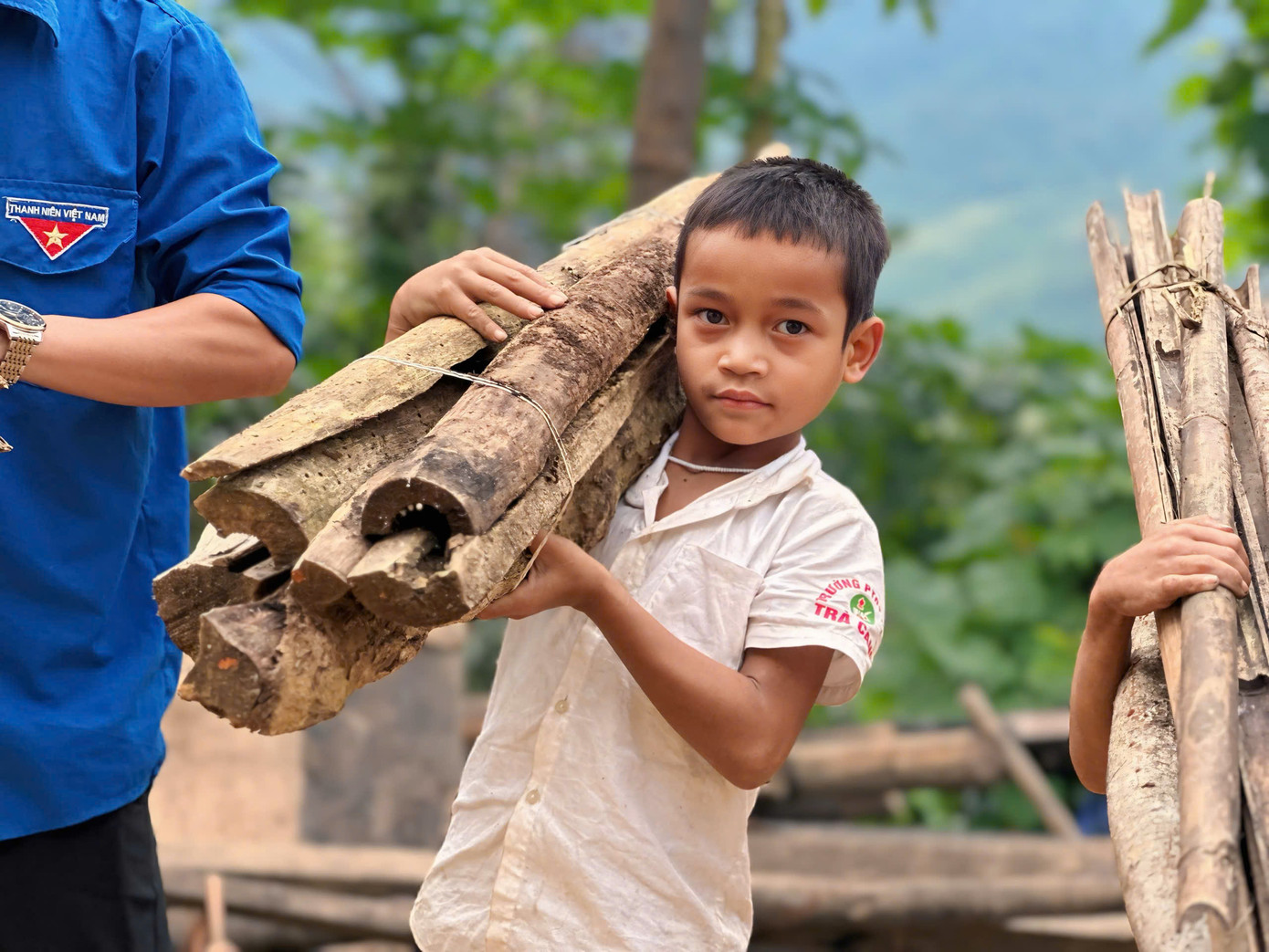 Đáng yêu hình ảnh các bạn nhỏ xung phong vác củi giúp anh chị chuẩn bị bữa ăn nhân ái.