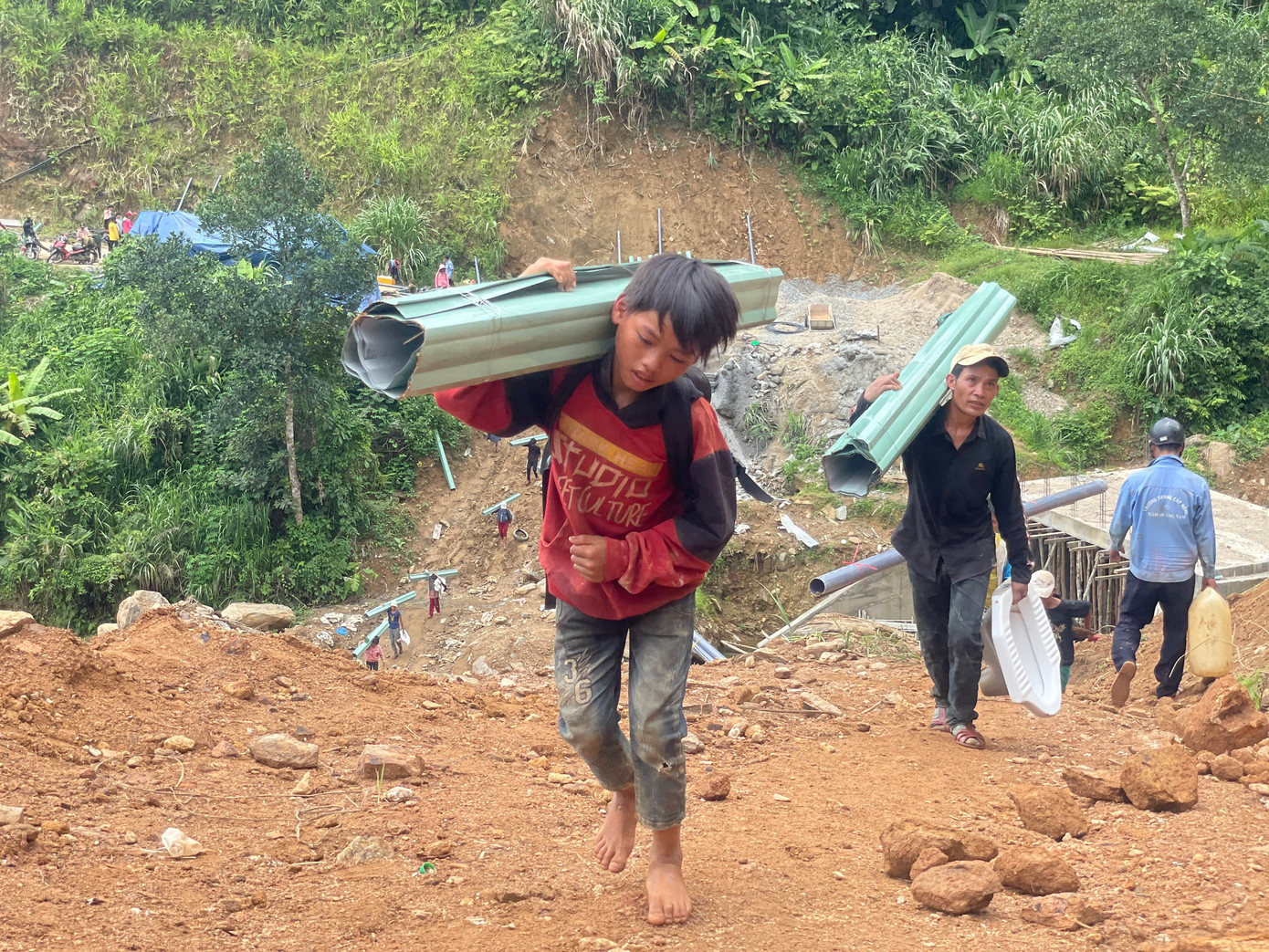 Mọi người cùng nhau lội bộ vận chuyển vật liệu về làng.
