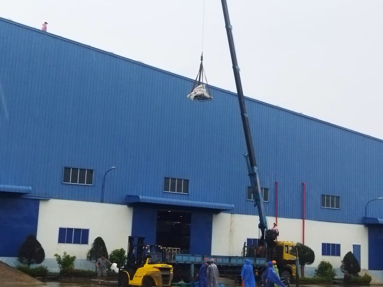Các bao cát được cẩu lên chằng chống mái nhà kho, khu sản xuất của công ty TNHH MTV Panko Tam Thăng Các bao cát được cẩu lên chằng chống mái nhà kho, khu sản xuất của công ty TNHH MTV Panko Tam Thăng