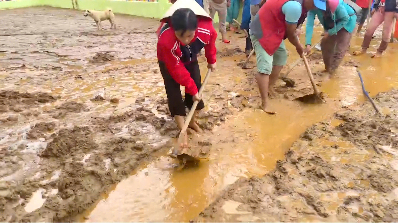 Cô Trà Thị Thu, giáo viên điểm trường cùng bà con và các lực lượng cào lớp bùn nhầy nhụa đặc quánh trên sân trường.
