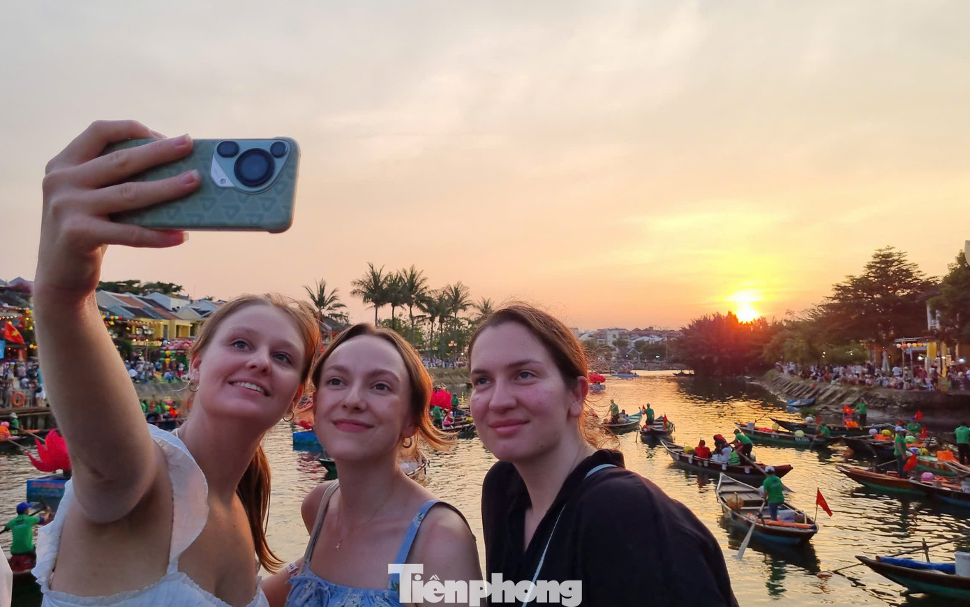 Nhóm du khách nước ngoài bắt trọn khoảnh khắc hoàng hôn nơi phố cổ Hội An. Ảnh: Hoài Văn.