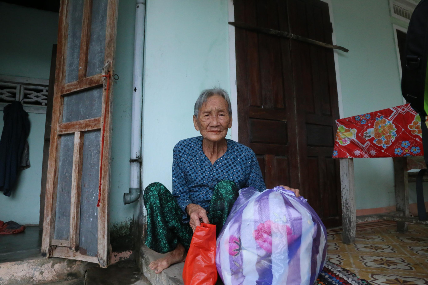 Nhà bà Trần Thị Khéo (78 tuổi, ở thôn Hòa Thượng, xã Tam Thanh) thuộc diện phải di dời đến nơi an toàn. Chồng bà bị tai nạn gãy chân đã được hỗ trợ di dời trước. Trong khi các lực lượng chức năng hỗ trợ xúc cát, đưa lên mái, chằng chống lại ngôi nhà, bà Khéo gói ghém đồ đạc cẩn thận để chuẩn bị dời đi khi có lệnh.