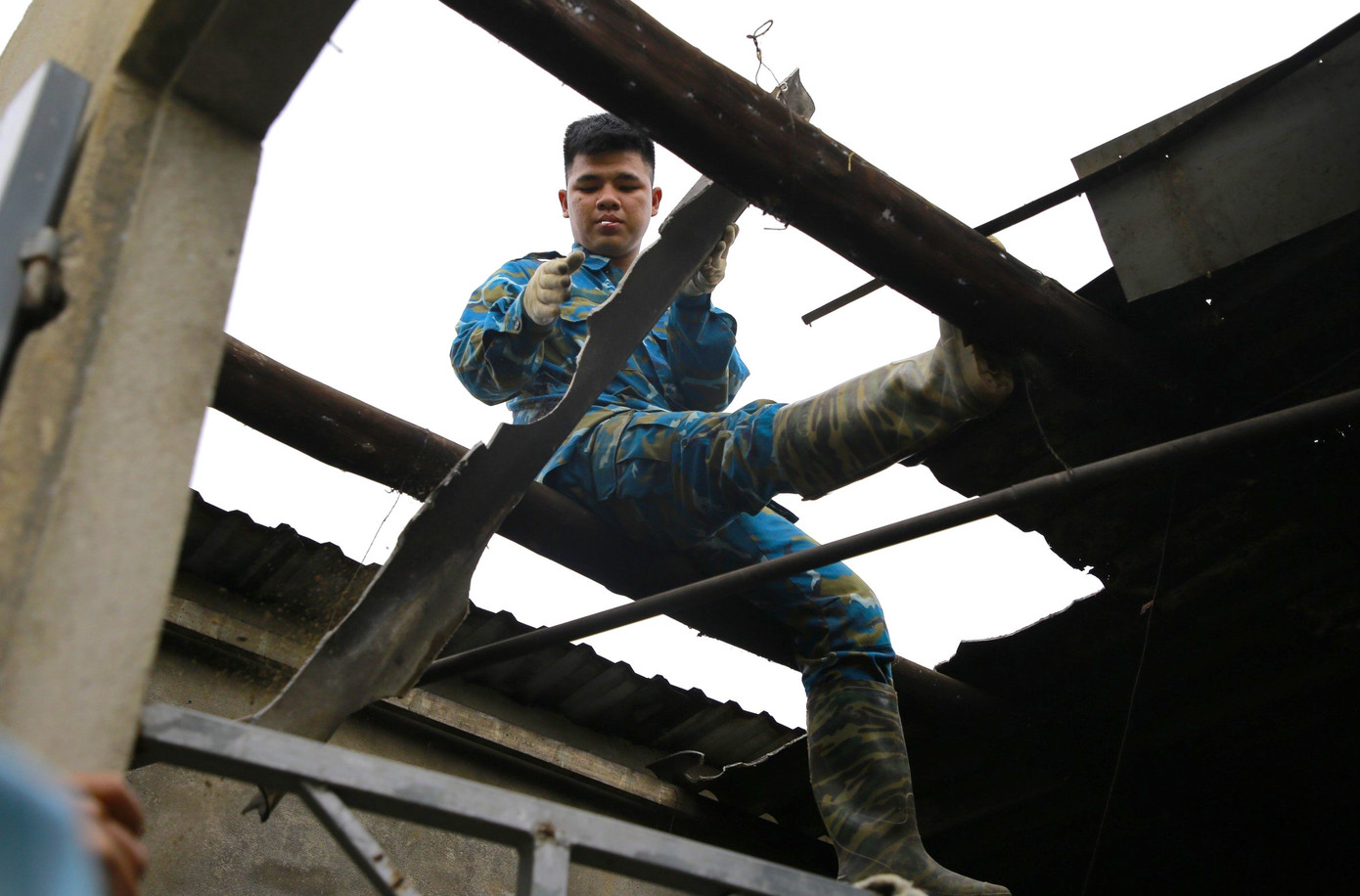 Các chiến sĩ dỡ mảnh tôn bị vỡ, lợp lại mới cho người dân.