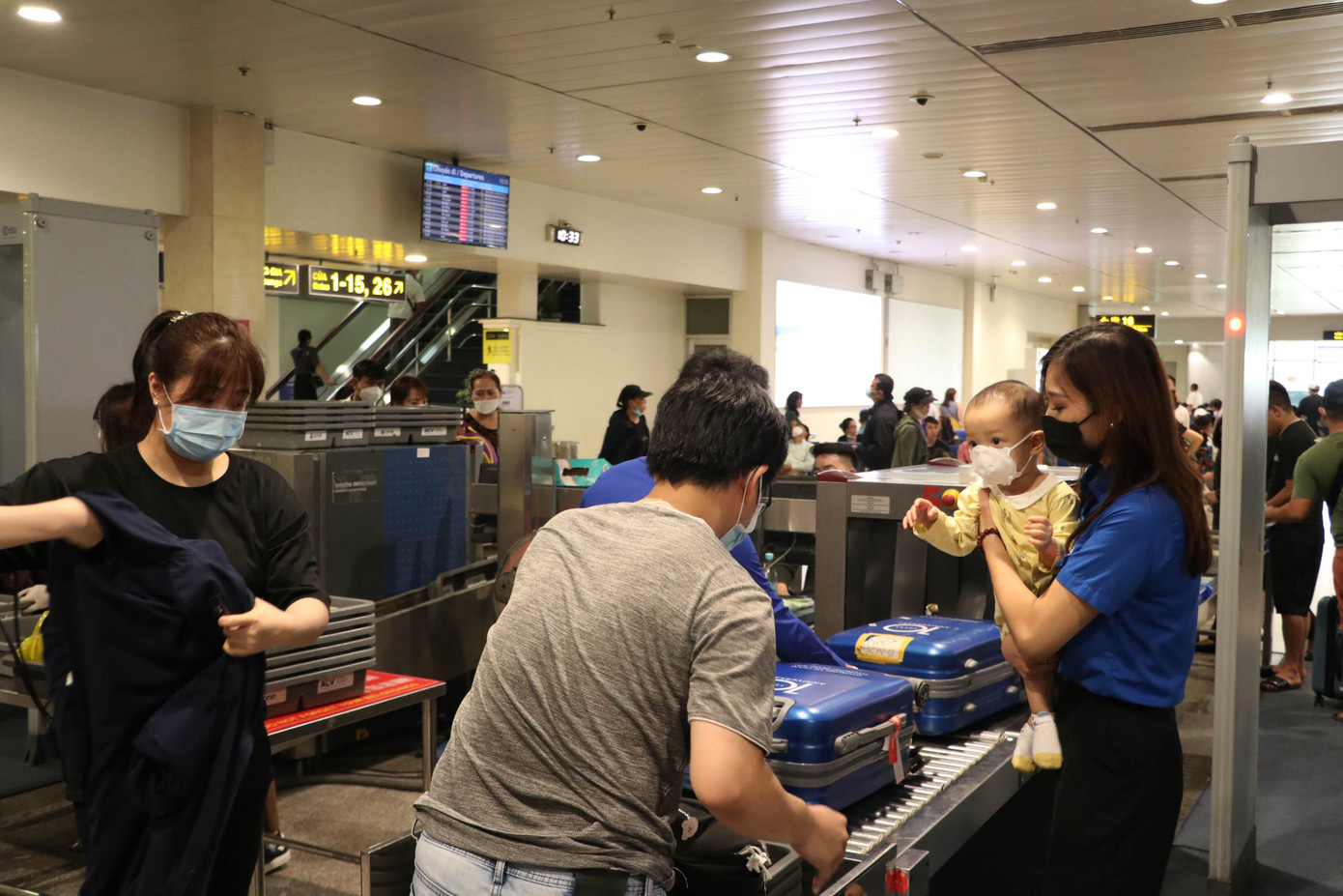 Tình nguyện viên hỗ trợ gia đình có em bé làm thủ tục kiểm tra an ninh.