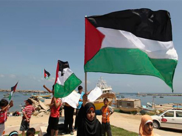 Người dân Palestine vẫy cờ tại cảng biển Gaza Ảnh: Reuters 