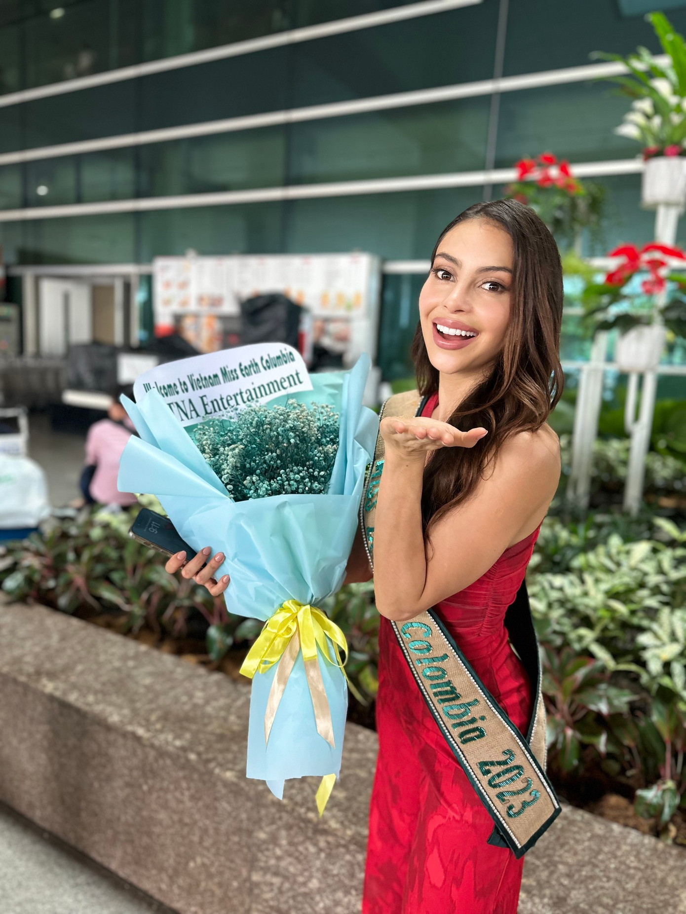 Người đẹp Colombia rạng rỡ ở sân bay Tân Sơn Nhất. Cô diện bộ jumpsuit màu đỏ nổi bật. Người đẹp là một trong những ứng viên mạnh của khu vực Mỹ Latinh, nhận được sự ủng hộ nhiệt tình từ người hâm mộ.