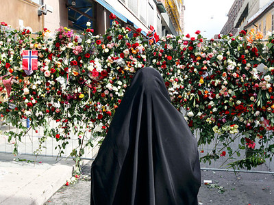 Một phụ nữ Hồi giáo đứng trước biển hoa đặt trước Thánh đường Oslo hôm 26-7