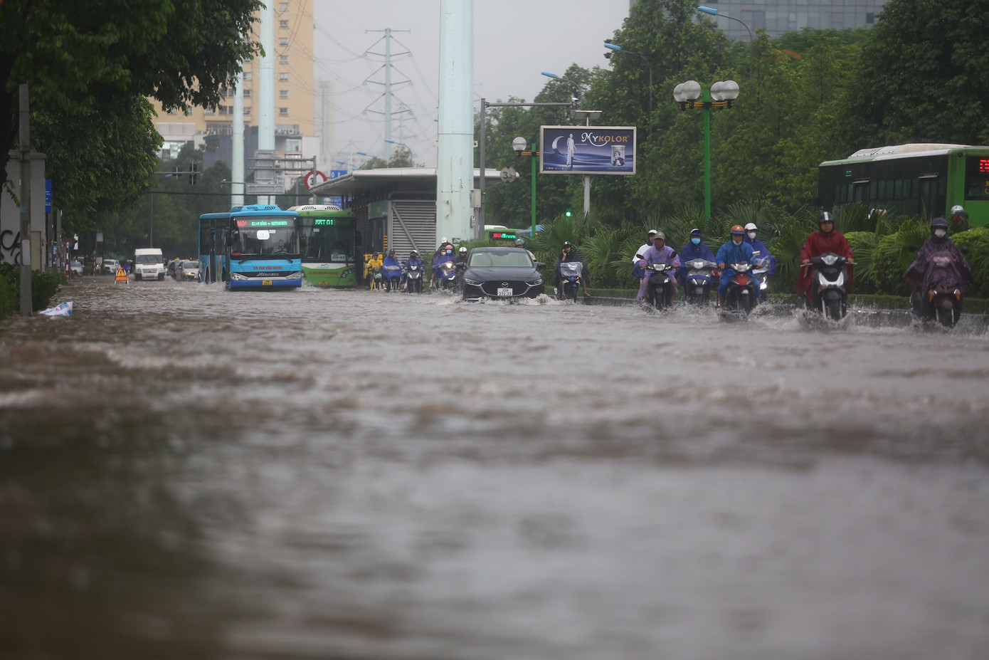 Các phương tiện chỉ có thể di chuyển thành một hàng sát dải phân cách để vượt khu vực ngập úng.