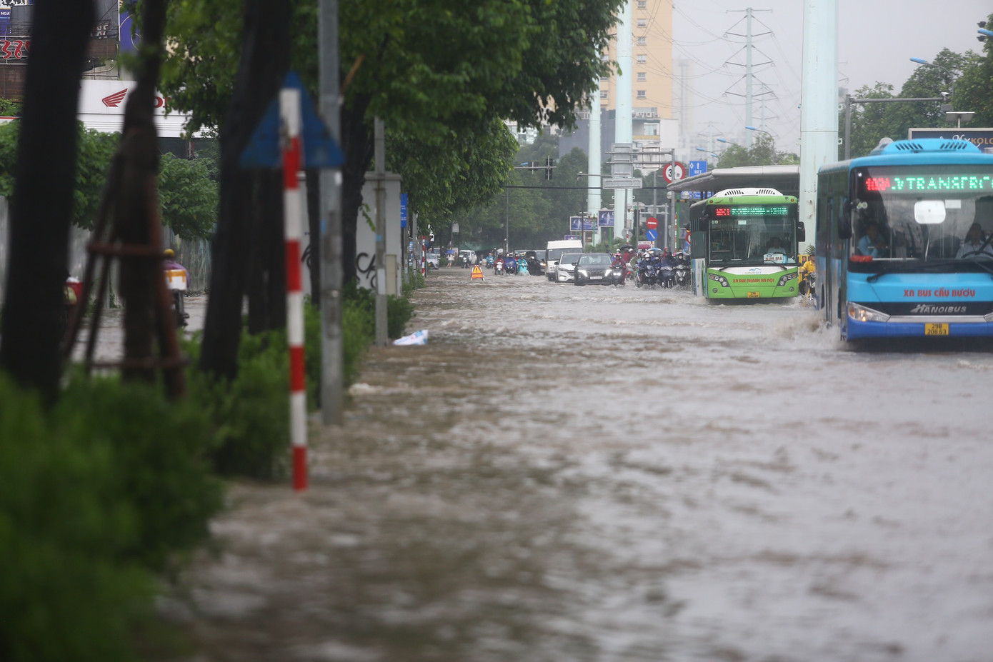 Các phương tiện chỉ có thể di chuyển thành một hàng sát dải phân cách để vượt khu vực ngập úng.