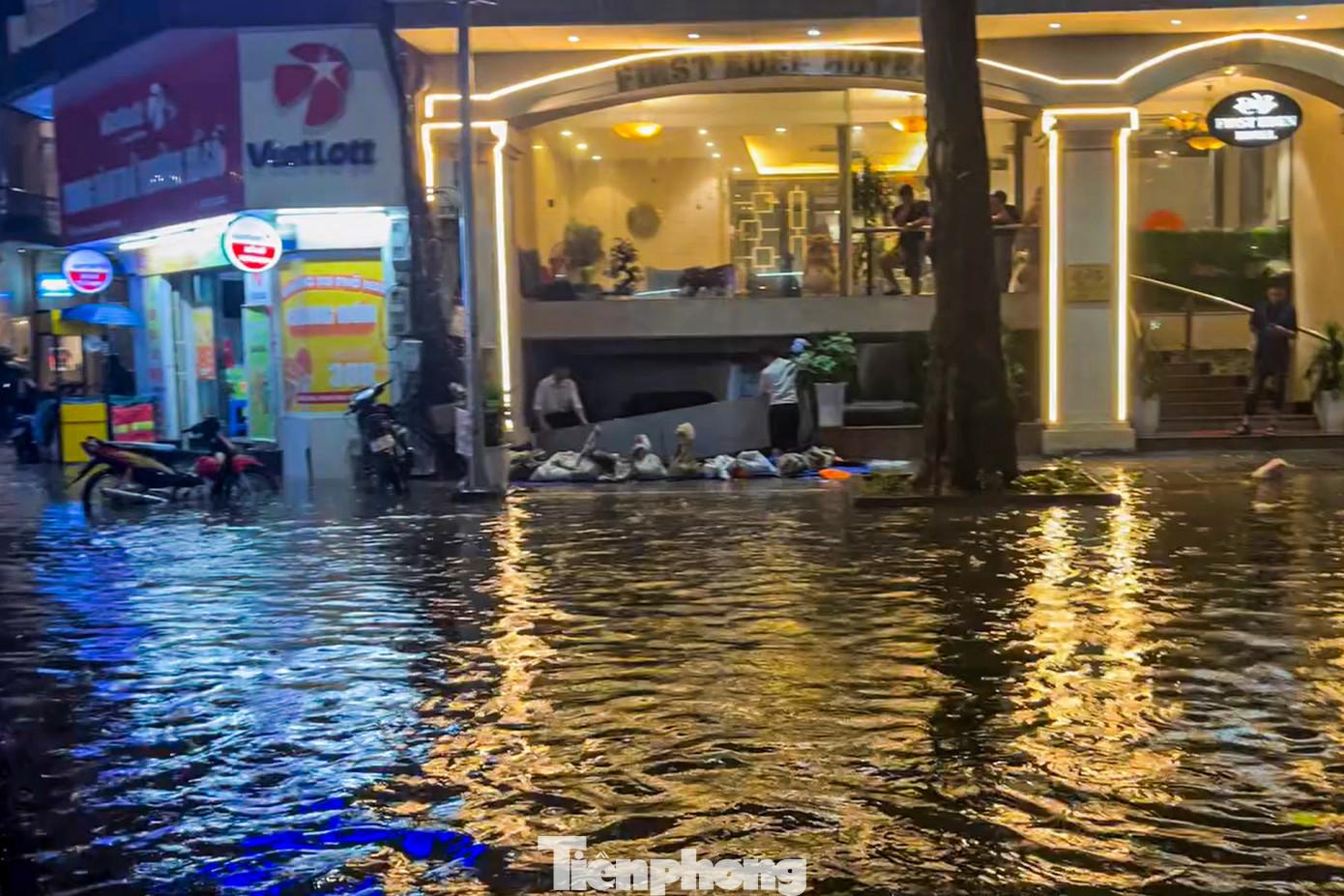 Nước tràn qua vỉa hè. Nhiều cơ sở phải dùng bao cát ngăn nước vào nhà.