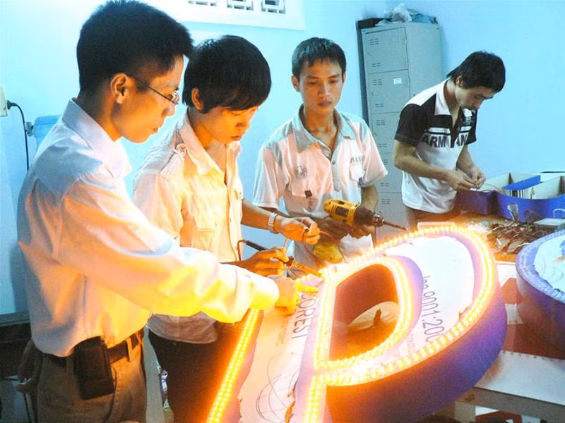 Nguyễn Ngọc Tân (bên trái) hướng dẫn Phan Duy Cần và các bạn sinh viên vừa học, vừa làm. Ảnh: Nguyễn Huy