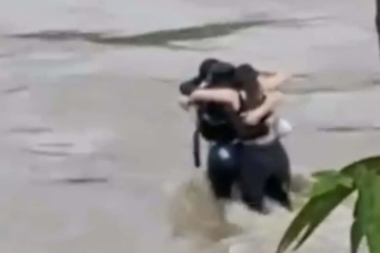 Hình ảnh ba người ôm nhau giữa dòng nước lũ. (Ảnh từ clip)