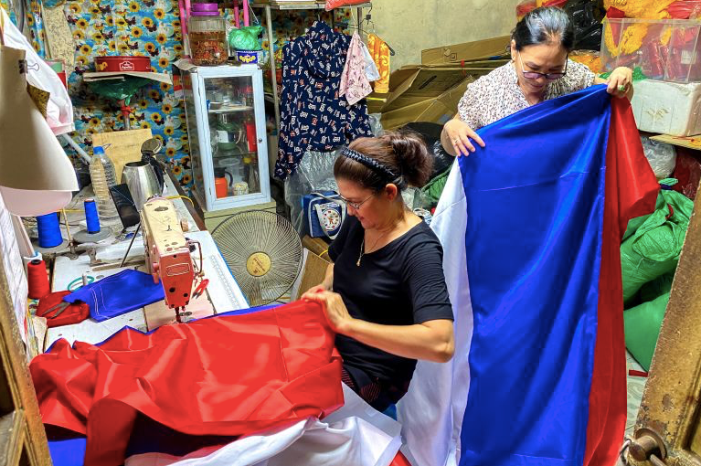 Bà Lê Kim Phương, 60 tuổi, và bà Lê Thu Hồng, 62 tuổi, đang may quốc kỳ Nga trước chuyến thăm của Tổng thống Nga Vladimir Putin tới Hà Nội. (Ảnh: Reuters)