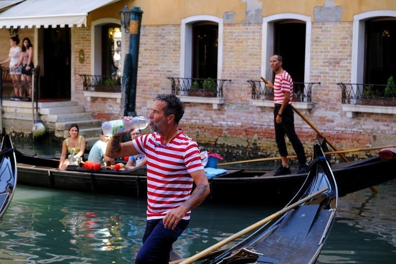Một người lái thuyền uống nước giữa tiết trời nắng nóng ở Venice (Ý). Ảnh: Reuters Một người lái thuyền uống nước giữa tiết trời nắng nóng ở Venice (Ý). Ảnh: Reuters