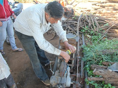 Ông Phan Ngọc Tấn bên chiếc máy cày gắn động cơ xe máy đang trong quá trình hoàn thiện