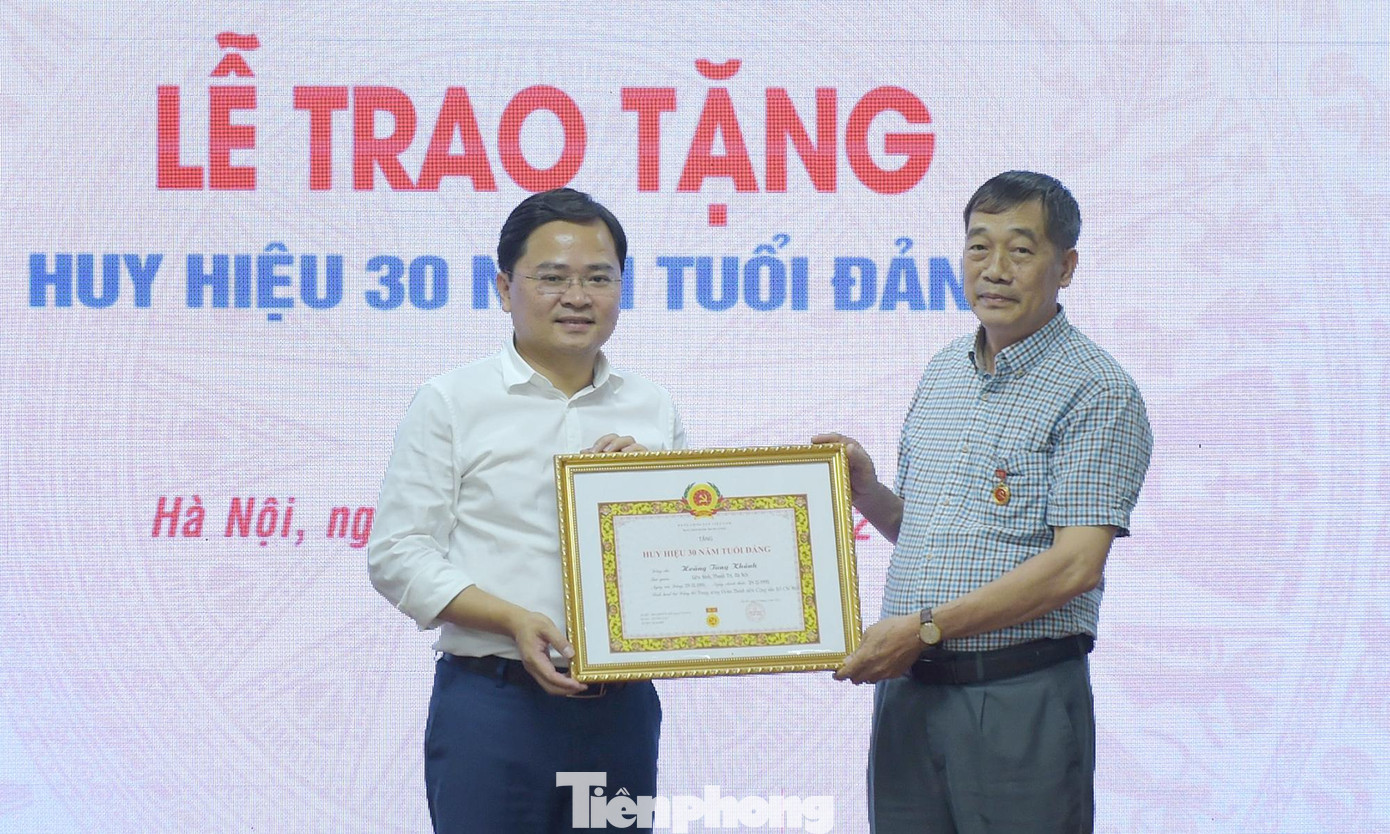 Anh Nguyễn Anh Tuấn trao huy hiệu 30 năm tuổi Đảng tặng ông Hoàng Tùng Khánh. Ảnh: Xuân Tùng