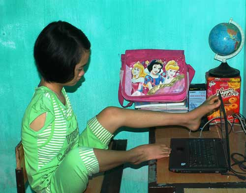 Thắm dùng chân mở máy vi tính