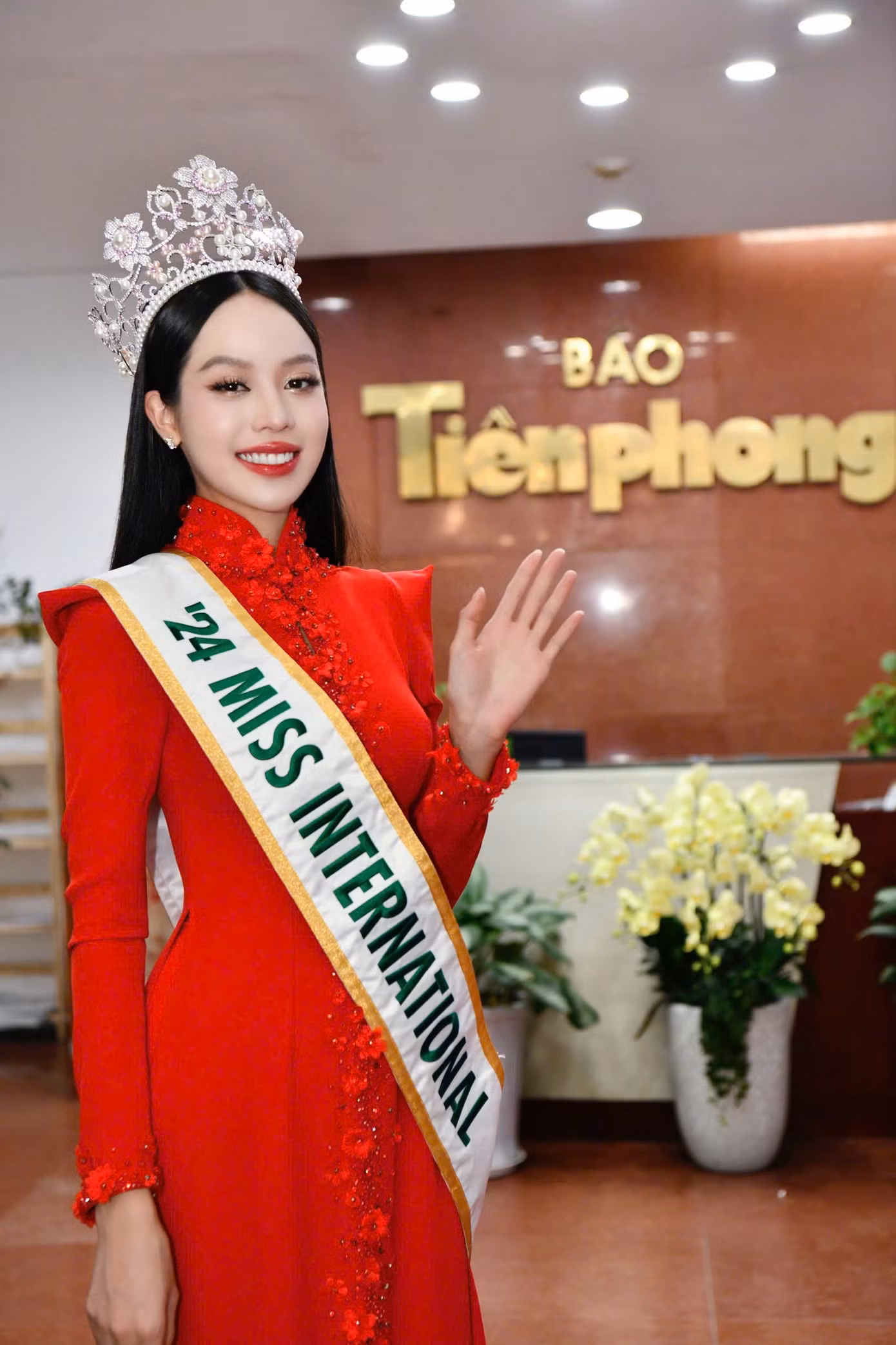 Người đẹp sinh năm 2002 xuất hiện rực rỡ trong tà áo dài truyền thống đỏ tươi và vương miện Hoa hậu Quốc tế 2024.