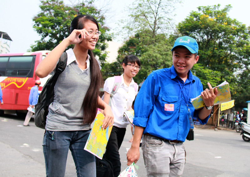 Một nữ thí sinh cười rất tươi vì được nam sinh viên tình nguyện xách hộ bao gạo. Ảnh: Trường Phong