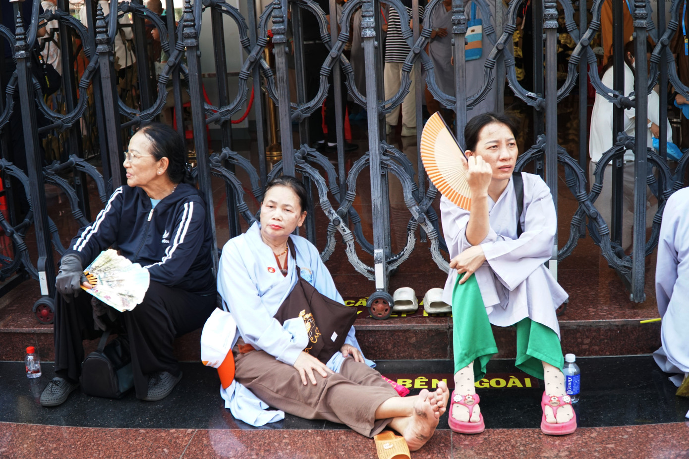 Nhiều người ngồi bệt dưới đất trong lúc chờ đợi.