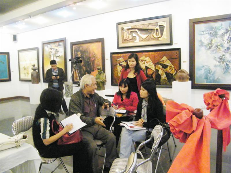 Họa sĩ Trần Khánh Chương trao đổi với nhà báo tại phòng triển lãm chào mừng ĐH Mỹ thuật toàn quốc. Ảnh: N.M.Hà